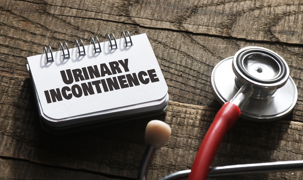 Urinary incontinence words in a notebook next to a stethoscope.